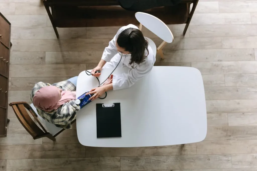 A female doctor checking a woman's blood pressure in a medical clinic, highlighting women's health problems and solutions, including preventive care and primary healthcare for better well-being.