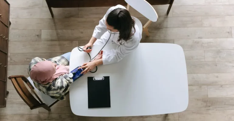 A female doctor checking a woman's blood pressure in a medical clinic, highlighting women's health problems and solutions, including preventive care and primary healthcare for better well-being.